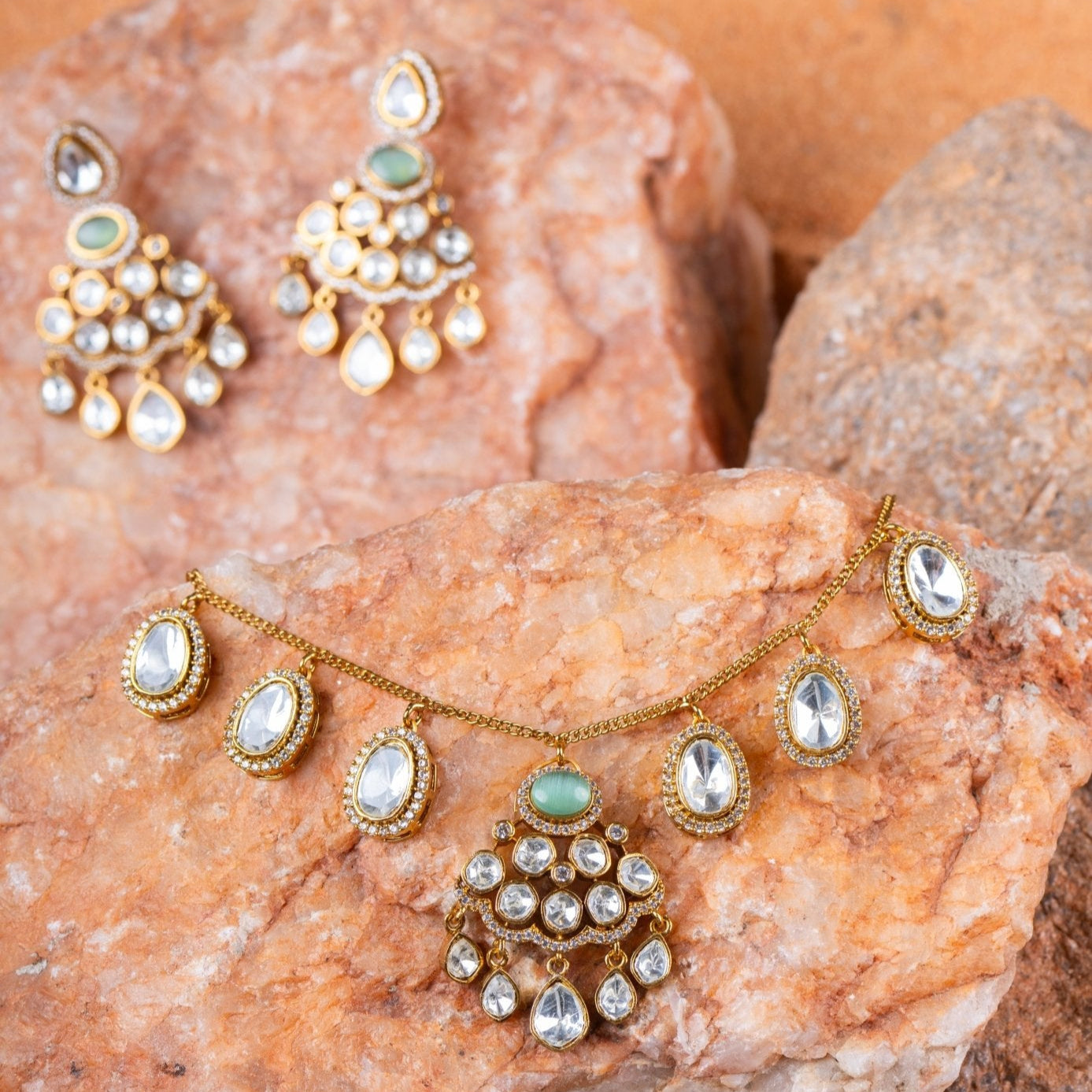 Gold jewelry set with gemstones on a textured stone surface