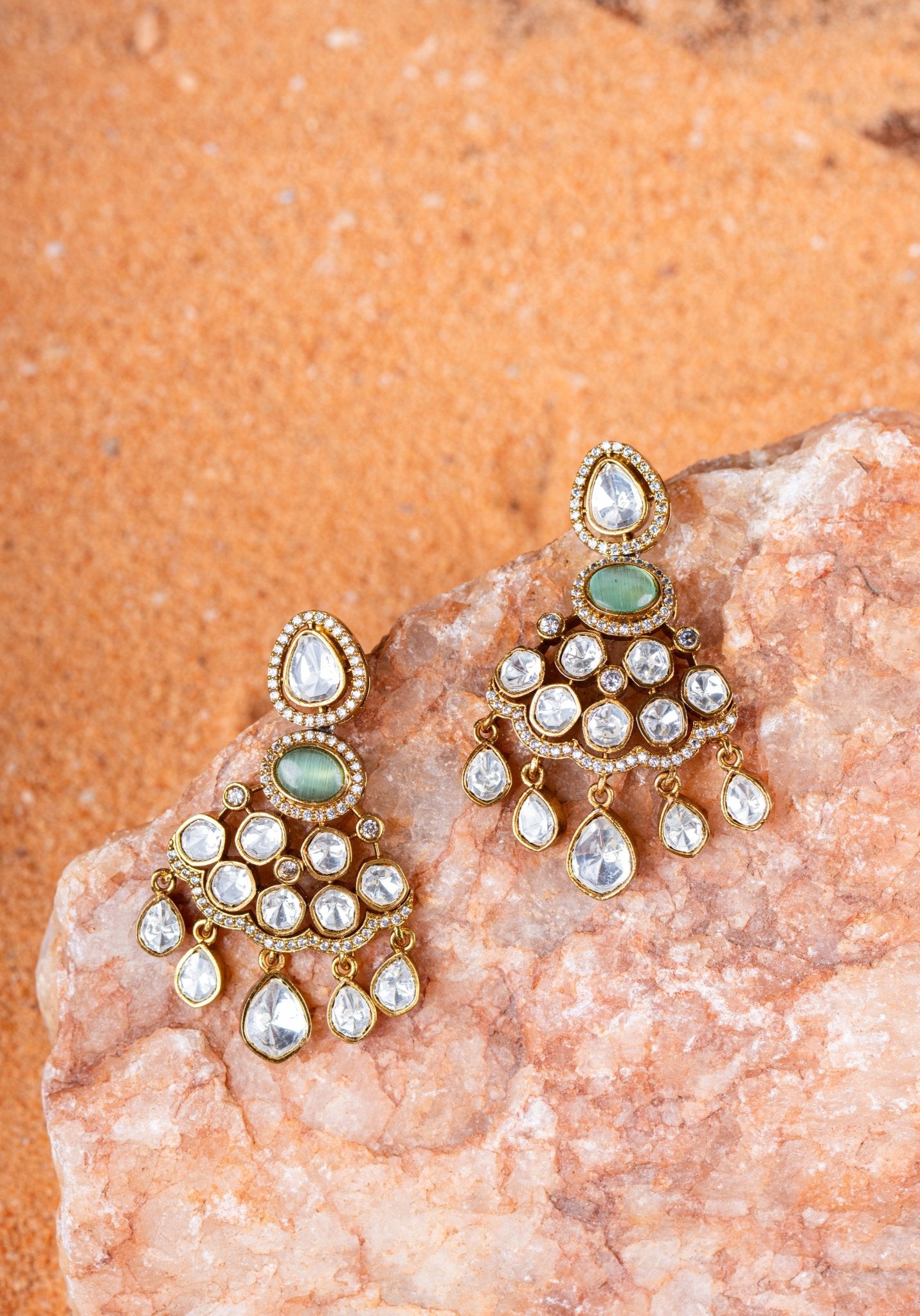 Ornate earrings with gemstones on a textured stone surface
